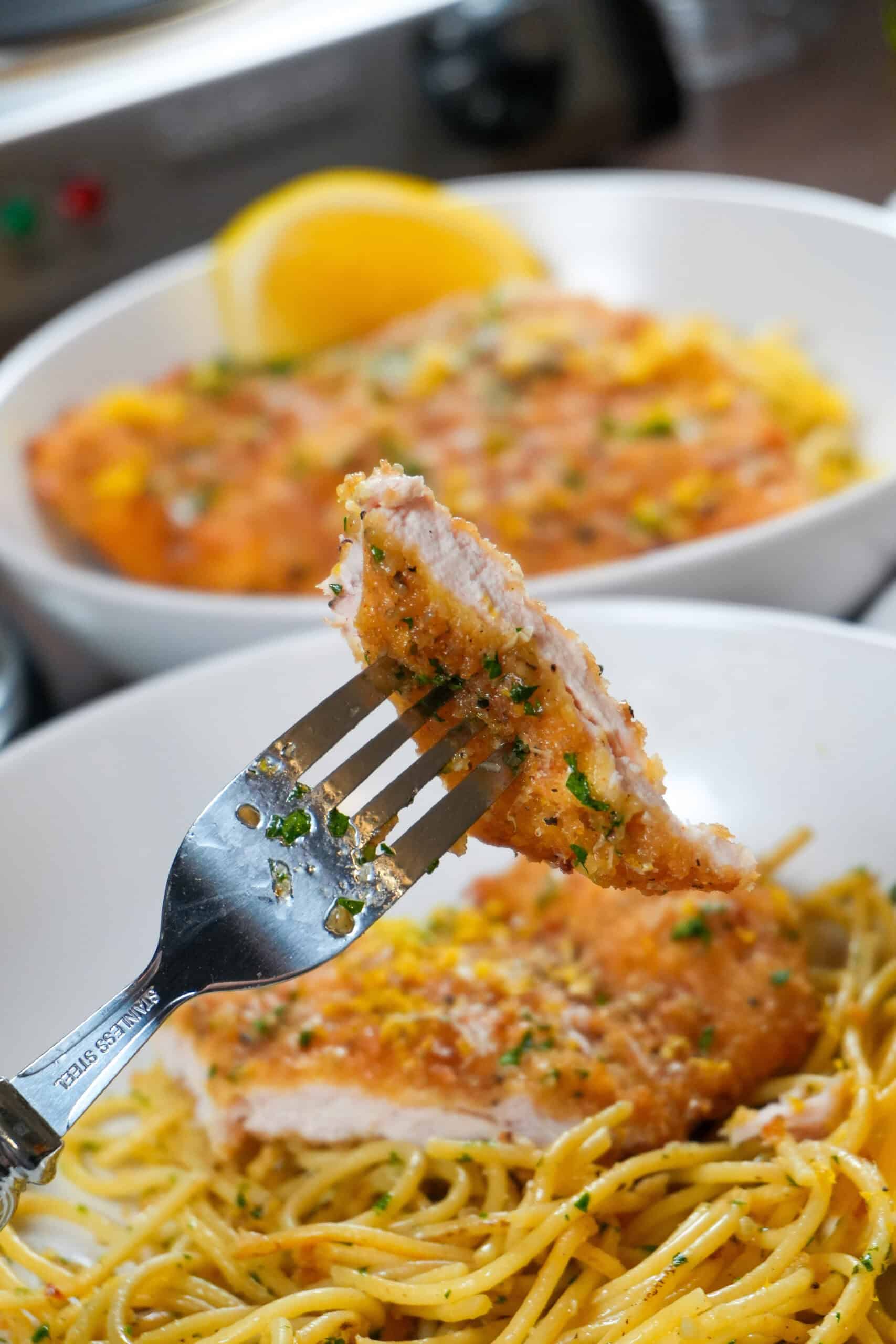 Crispy fried wet lemon pepper chicken with pasta and herbs on a plate, inviting home-cooked meal presentation.